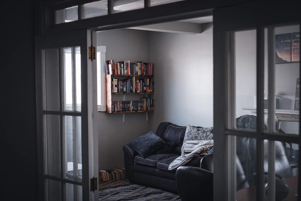 Comfortable lived-in reading room with book-lined shelves and a worn couch in a quiet Maine outpatient community clinic.